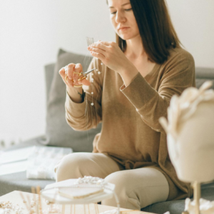 Adult woman focused on crafting handmade jewelry with beads indoors.