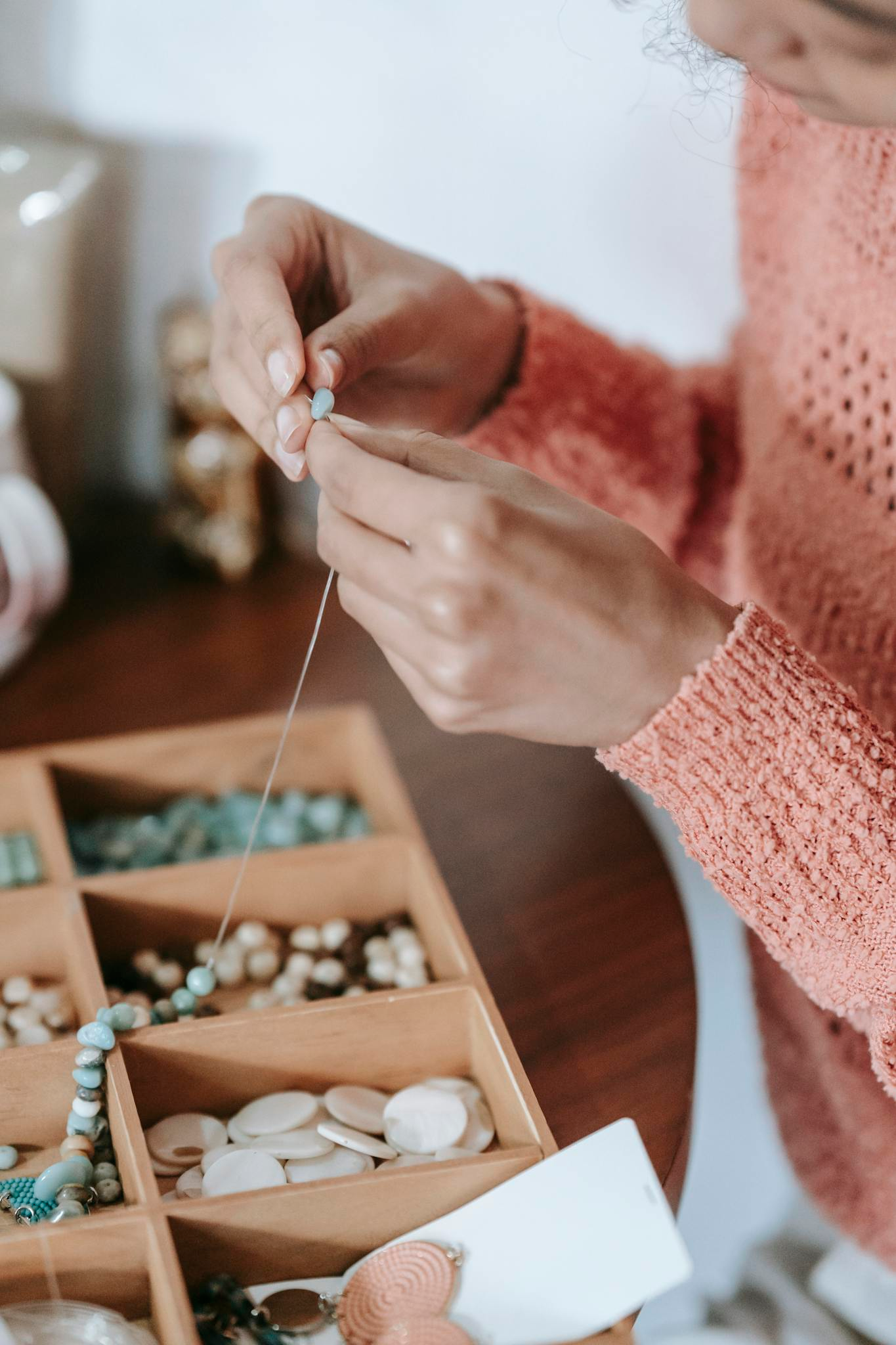 Photo by Miriam Alonso Anonymous female arranging beads and blue natural stones on fishing line while doing handmade bijouterie