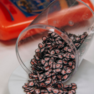 Charming paw-shaped beads spilling from a transparent cup onto a surface.