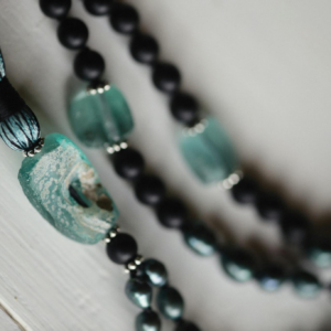 Close-up of a beaded jewelry piece with teal accents, emphasizing spirituality and craftsmanship.
